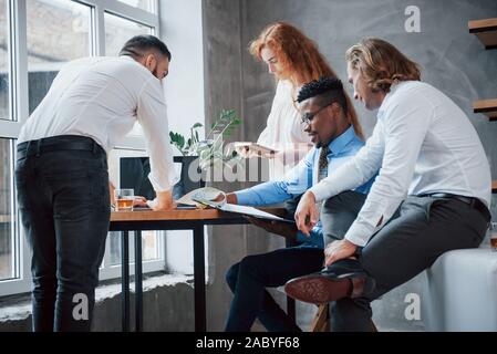 Projekt diskutieren. Gruppe der multirassischen Büroangestellte in formelle Kleidung sprechen über Aufgaben und Pläne Stockfoto