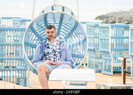 Schöner Mann ruht auf einer Schaukel bärtigen. empört Kerl Stockfoto