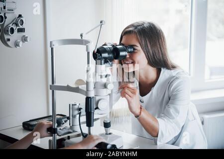 Junge weibliche Arzt mit dem Auge Prüfmittel und lächelnd Stockfoto