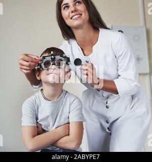 Können Sie sehen, was dort geschrieben wird. Arzt tuning Der phoroptor an Sehschärfe des kleinen Jungen bestimmen Stockfoto