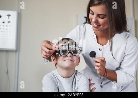 Dies ist Spaß. Arzt tuning Der phoroptor an Sehschärfe des kleinen Jungen bestimmen Stockfoto