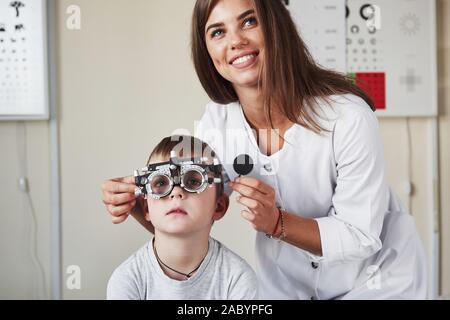 Arbeit ist im Gange. Arzt tuning Der phoroptor an Sehschärfe des kleinen Jungen bestimmen Stockfoto