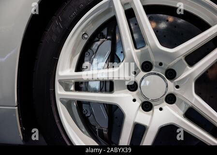 Nahaufnahme von weißen Leichtmetallräder mit Bremsscheibe pad, niederquerschnittsreifen eines modernen Sport Auto Stockfoto