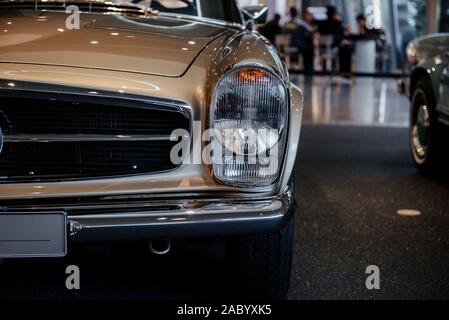 Close-up des Scheinwerfers links von Retro beige Cabrio Auto mit Chrom Außenspiegel, Stoßfänger und kühler Verkleidung Stockfoto