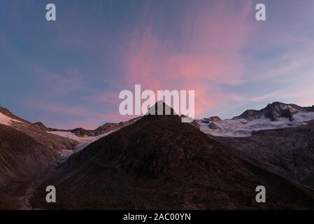 Der pyramidenförmige Berg Steinmandl vor der Gletscher, Berggipfel und die rötlichen Schleier Wolken bei Sonnenuntergang an der Berliner Hütte, Zillertal Stockfoto