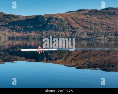 Derwentwater Keswick Cumbria, Großbritannien. 29 Nov, 2019. Man Reihe über einen stillen See in schönen Reflexionen im Lake District Landschaft heute auf einem Einfrieren und klaren sonnigen Wintertag. Das kalte Wetter über das Wochenende mit einem harten Frost über Nacht, um fortzufahren. Credit: Julian Eales/Alamy leben Nachrichten Stockfoto