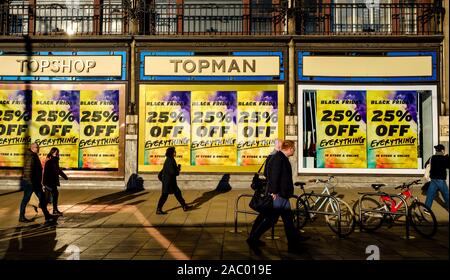 Menschen zu Fuß vorbei" Poster Black Friday' in einem Schaufenster in der Princes Street, Edinburgh am 29. November 2019 Stockfoto