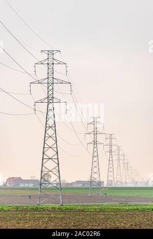 Die Verteilung von Strom. Hohe Spannung Oberleitung, Strommast, Stahl Gittermast stehend auf dem Feld. Blauen Himmel als Hintergrund. Stockfoto