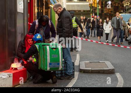 Borough Market, London, Großbritannien. November 2019. Die Rettungsdienste reagieren auf einen Messerstecher auf die London Bridge, der eine von der Polizei geführte Evakuierung in der Nähe des Borough Market veranlasste. Das Bild zeigt Sanitäter, die einen verletzten Fußgänger in einem abgesperrten Bereich betreuen, während die Polizei die Umgebung absichert. Der Vorfall, der als Terrorismus behandelt wurde, störte das geschäftige Marktviertel und zog eine bedeutende Notfallreaktion nach sich. Penelope Barritt/Alamy Live News Stockfoto