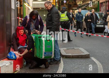 Borough Market, London, Großbritannien. November 2019. Die Rettungsdienste reagieren auf einen Messerstecher auf die London Bridge, der eine von der Polizei geführte Evakuierung in der Nähe des Borough Market veranlasste. Das Bild zeigt Sanitäter, die einen verletzten Fußgänger in einem abgesperrten Bereich betreuen, während die Polizei die Umgebung absichert. Der Vorfall, der als Terrorismus behandelt wurde, störte das geschäftige Marktviertel und zog eine bedeutende Notfallreaktion nach sich. Penelope Barritt/Alamy Live News Stockfoto