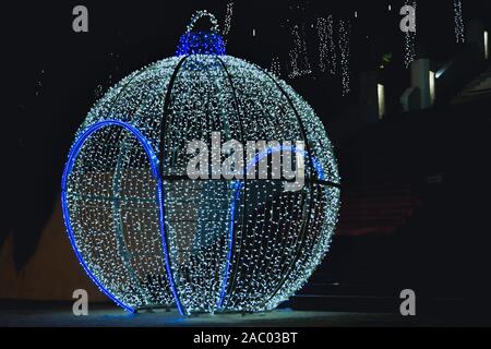 Eine sehr große und begehbare Christmas Ball als Dekoration für die Weihnachtszeit mit vielen Lichtern und einem blau leuchtenden Grenze. Stockfoto