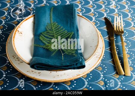 Festlich gedeckten Tisch Platz für Weihnachten oder Neujahr Familie Abendessen mit Winter Dekor. Golden Besteck, Keramik Geschirr mit Anlage auf einer Serviette dekoriert. Stockfoto