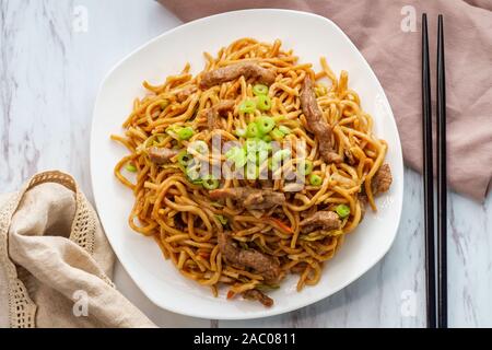 Essen chinesisch Rindfleisch lo mein Nudeln mit Stäbchen Stockfoto