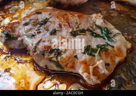 Kochen Salbei und Rosmarin gebratene Schweinekoteletts in Topf auf Herd Stockfoto