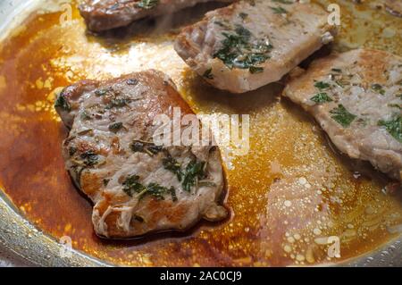 Kochen Salbei und Rosmarin gebratene Schweinekoteletts in Topf auf Herd Stockfoto