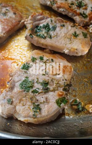 Kochen Salbei und Rosmarin gebratene Schweinekoteletts in Topf auf Herd Stockfoto