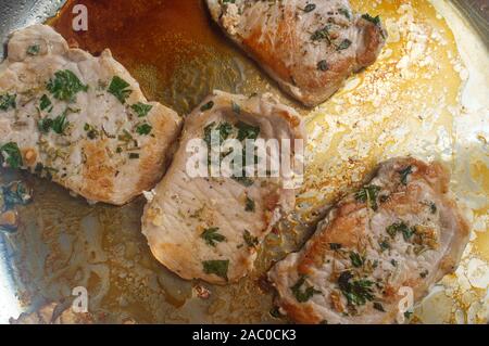 Kochen Salbei und Rosmarin gebratene Schweinekoteletts in Topf auf Herd Stockfoto