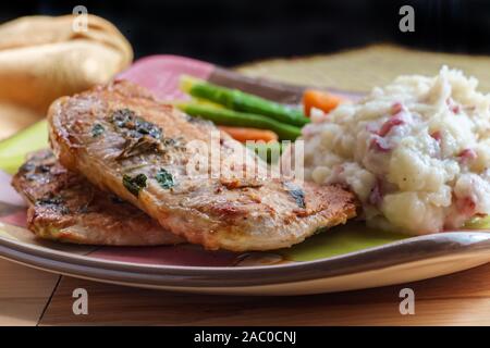 Salbei und Rosmarin BBQ Schweinekoteletts mit Haut - auf Kartoffelpüree und grünen Bohnen Stockfoto