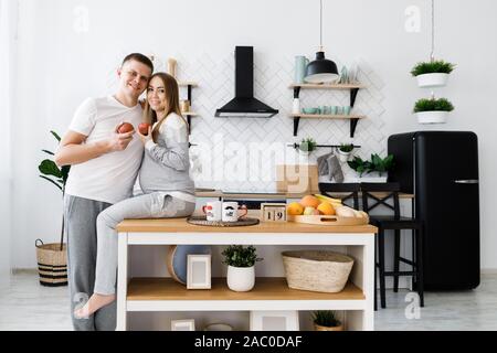 Junges Paar - Mann und Frau Baby erwarten, die Zeit in der Küche, das Essen von Früchten. Stockfoto