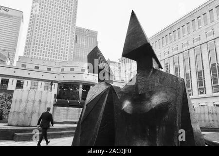 Canary Wharf, London, Großbritannien - 22 November 2019: Paar auf einem Sitz, der durch Lyn Chadwick 1984, Stahlskulptur. Cabot Square, aussen. Stockfoto