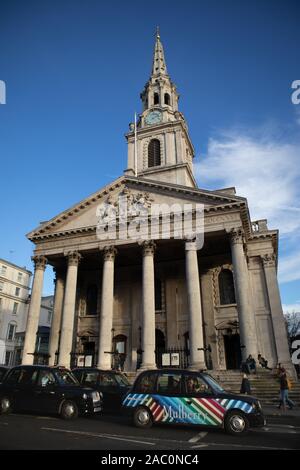 London Taxis, schwarze Taxis fahren St. Martin-in-the-Fields, Anglikanische Kirche an der nord-östlichen Ecke der Trafalgar Square London England Stockfoto