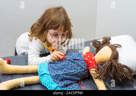 Kind, Mädchen spielen Arzt mit einem Spielzeug. Beruf und Pflege Konzept. Neutrale Hintergrund. Stockfoto