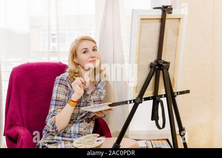 Frau Künstler mit Aquarell und Staffelei sieht in dem Rahmen beim Erstellen Stockfoto