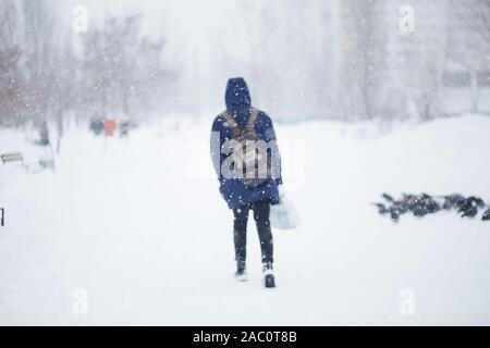 Von einem Mann entlang eine verschneite Straße. Starker Schneefall in der Stadt. Verschwommenes Bild von einem Mann. Web Promo Banner Hintergrund für Werbung Stockfoto