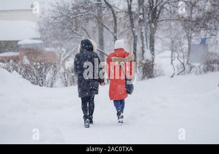 Von einem Mann entlang eine verschneite Straße. Starker Schneefall in der Stadt. Verschwommenes Bild von zwei Mädchen. Web Promo Banner Hintergrund für Werbung Stockfoto