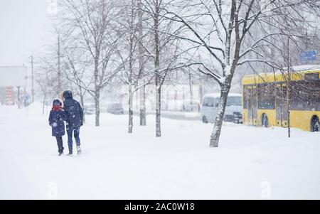 Von einem Mann entlang eine verschneite Straße. Starker Schneefall in der Stadt. Verschwommenes Bild von Mutter und dauther. Web Promo Banner Hintergrund für Ad Stockfoto