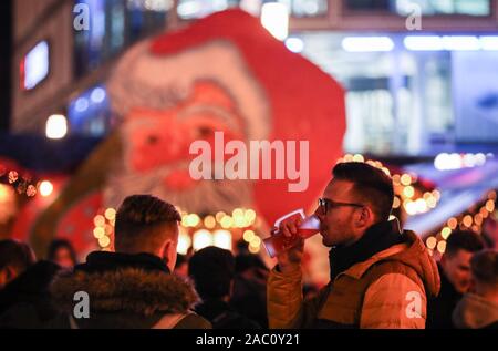 Berlin, Deutschland. 29 Nov, 2019. Ein Besucher getränke Glühwein auf dem Weihnachtsmarkt auf dem Alexanderplatz in Berlin, Deutschland, an November 29, 2019. Credit: Shan Yuqi/Xinhua/Alamy leben Nachrichten Stockfoto