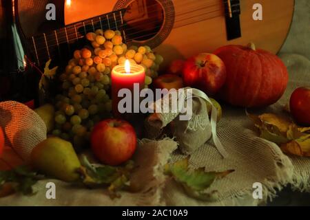 Herbst warm Szene. Noch Leben ernten. Thanksgiving post card Grüße. Kerze mit reifen Früchten und einer Flasche Wein. Stockfoto