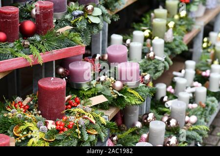 Traditionelle Adventskranz mit einzelnen großen, dunklen Rot, Rosa und weissen Kerzen und saisonale Weihnachtsschmuck auf hölzernen Regal für Verkauf vor Fl Stockfoto