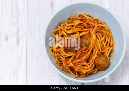 Spaghetti mit Fleischbällchen in eine Tomate Sušice mit Kräutern und Gewürzen in einem grünen Schüssel. Auf einem grauen Holz Oberfläche Stockfoto