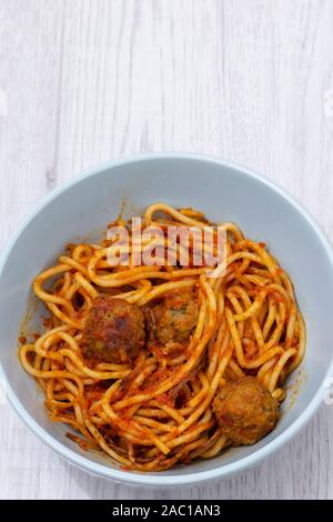 Spaghetti mit Fleischbällchen in eine Tomate Sušice mit Kräutern und Gewürzen in einem grünen Schüssel. Auf einem grauen Holz Oberfläche Stockfoto