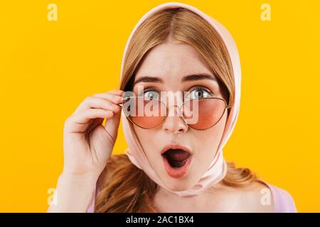 Bild eines jungen Mädchens schockiert über gelb Wand Hintergrund tragen Brillen und Schal isoliert. Stockfoto