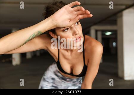 Bild des schönen netten Frau in Sportkleidung ruht während der Arbeit aus auf den Parkplatz Stockfoto