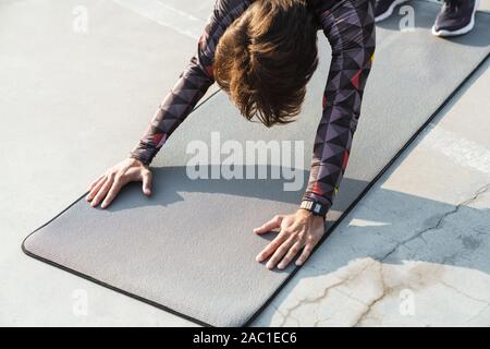 7/8-Foto von athletischen Mann in Sportswear Übungen auf der Matte, während sie auf dem Spielplatz im Freien arbeiten Stockfoto