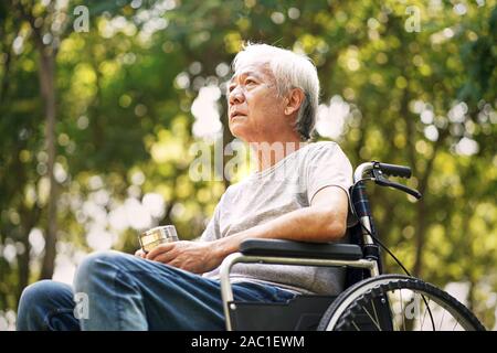 Asiatische alte Mann sitzt im Rollstuhl, traurig und deprimiert Stockfoto