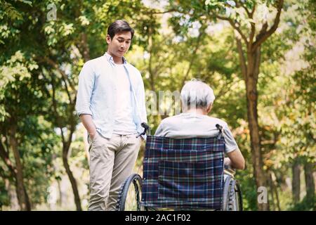 Asiatische Sohn sprechen zu traurig und deprimiert Rollstuhl Vater Stockfoto