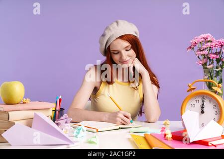 Foto der hübschen Studentin Mädchen schreiben, die in der übung Buch, während der Hausarbeit über lila Hintergrund isoliert Stockfoto