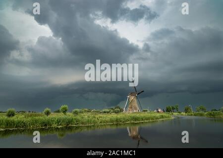 Klassische holländische Windmühle mit einem stürmischen Himmel im Hintergrund. Shelfcloud von einem schweren Gewitter über die weite, offene Landschaft von Holland. Stockfoto