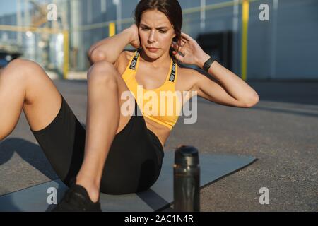 Bild der brünette Frau in Sportkleidung, Crunches auf Fitness Matte im Freien Stockfoto