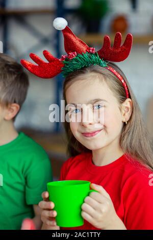 Guten Morgen. Ein nettes verschlafenes girl Getränke Kaffee am Küchentisch und umarmt einen Teddybären in der Küche sitzt. Eine Zeit der Wunder und Erfüllung von d Stockfoto