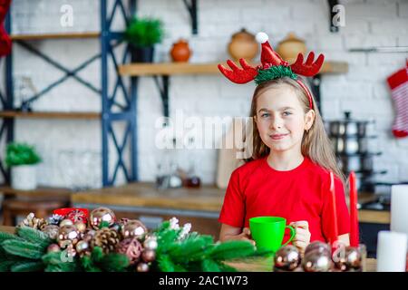 Guten Morgen. Ein nettes verschlafenes girl Getränke Kaffee am Küchentisch und umarmt einen Teddybären in der Küche sitzt. Eine Zeit der Wunder und Erfüllung von d Stockfoto