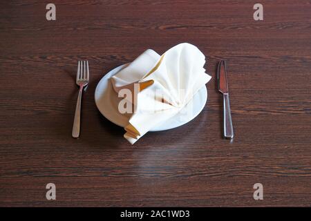 Handtuch auf weissen Teller, Messer und Gabel auf hölzernen Tisch Stockfoto