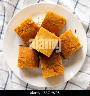 Hausgemachte geschnitten Cornbread bereit zu Essen, auf eine weisse Platte, Ansicht von oben. Flach, Overhead, von oben. Nahaufnahme. Stockfoto