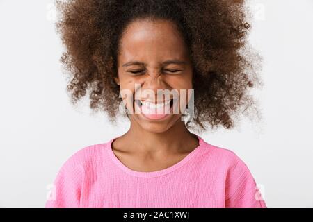 Fröhliche lustige kleine afrikanische Mädchen mit rosa Bluse auf weißem Hintergrund, Grimassen, die Zunge heraus Stockfoto