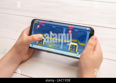 Sarajevo, Bosnien und Herzegowina - 30. November 2019: JetPack JoyRide Plattform Spiel auf moderne smart phone in Kid Hände close-up Stockfoto