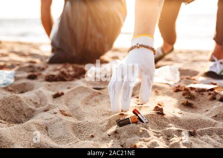 Die jungen Freiwilligen paar Reinigung Strand von Müll, Abholung Batterien Stockfoto